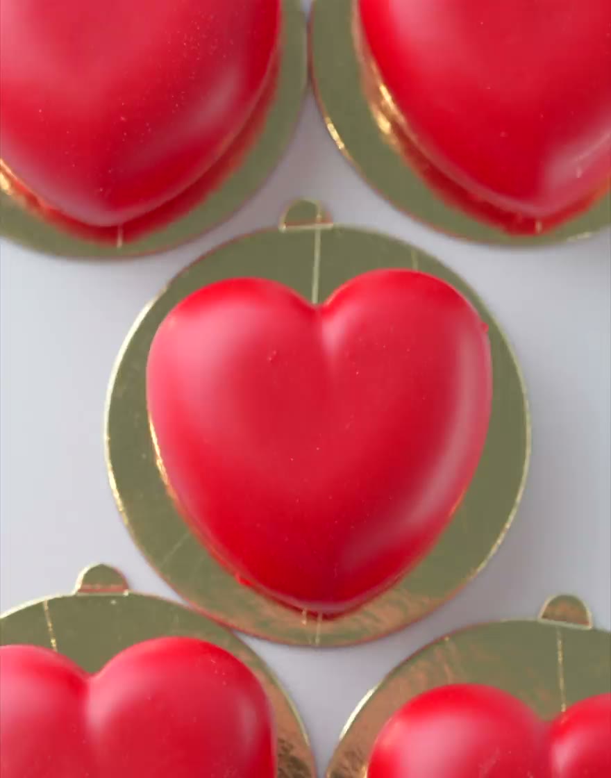Red heart-shaped mousse cakes on gold boards